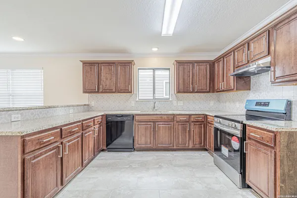 a large kitchen with a large counter top a sink a stove a refrigerator cabinets and a window