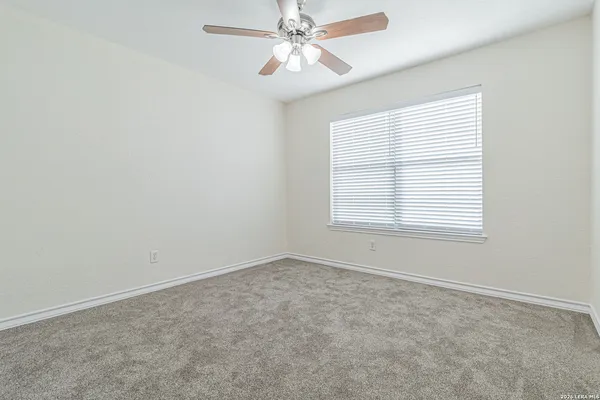 an empty room with a window and a fan