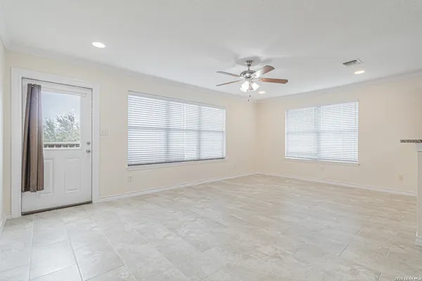 an empty room with chandelier fan and windows