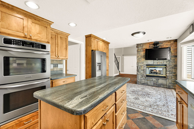 4792 Glasmann Way South Ogden, UT 84403 - Photo 43 of 70 Kitchen island with a striated countertop, surrounded by wood cabinetry and with dual ovens