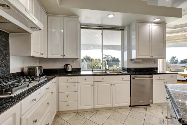 a kitchen with granite countertop white cabinets sink and stainless steel appliances
