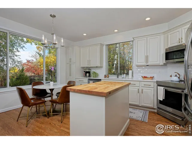 a kitchen with stainless steel appliances granite countertop a stove a sink a microwave and white cabinets