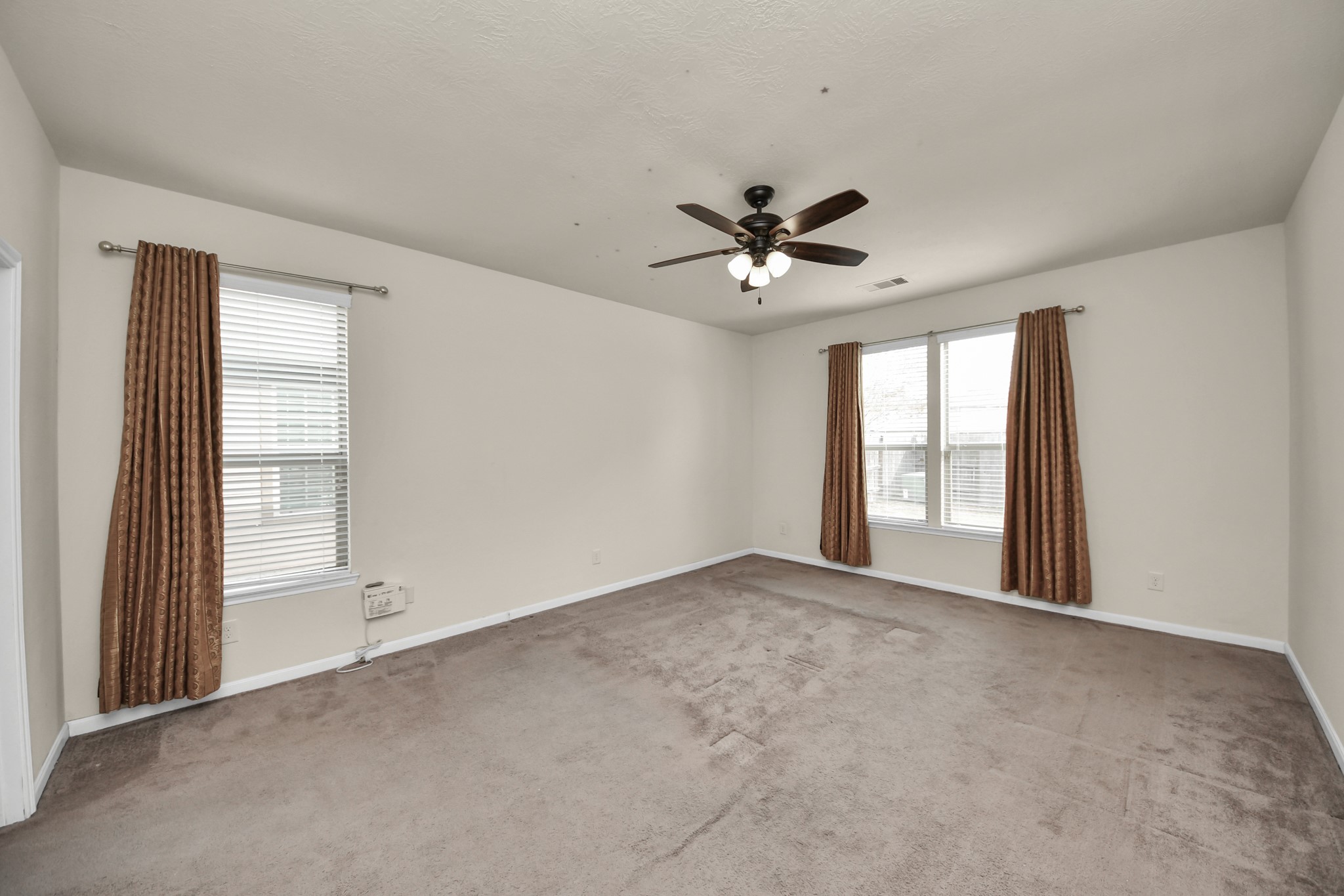 21119 Keystone Pine Court Katy, TX 77449 - Photo 22 of 43 Escape to the first floor Primary Suite, featuring clean and cozy carpet, an upgraded ceiling fan, and multiple windows with custom treatments offering lots of natural lights.