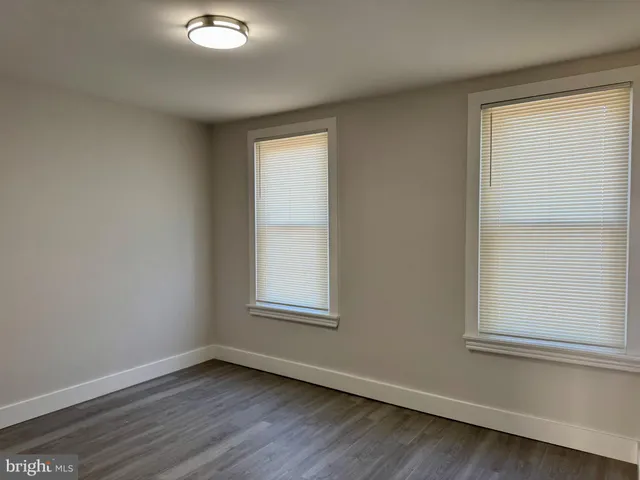 an empty room with wooden floor closet and windows