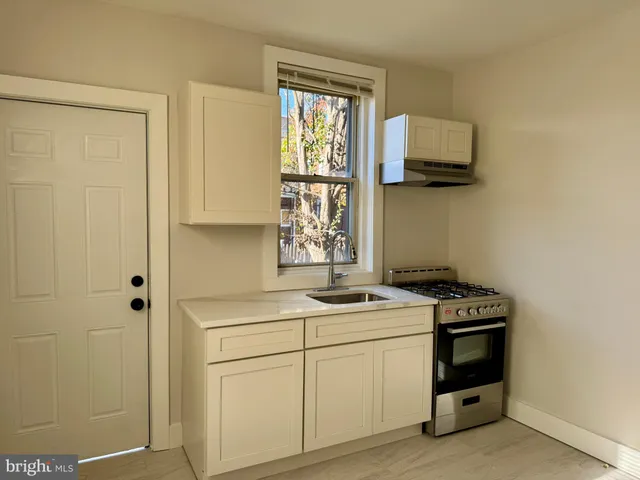 a utility room with a stove a sink and a window