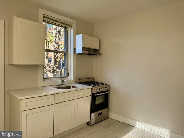 a kitchen with a stove a sink and a window