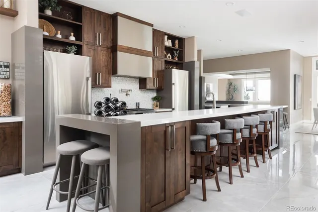 a kitchen with stainless steel appliances kitchen island granite countertop a table chairs sink and cabinets