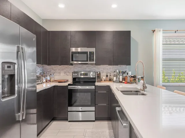 a kitchen with stainless steel appliances granite countertop a sink stove and refrigerator