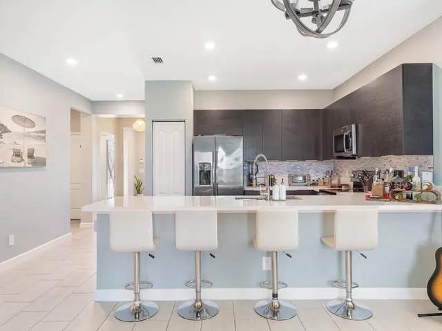 a kitchen with stainless steel appliances kitchen island granite countertop a table chairs in it and wooden floors