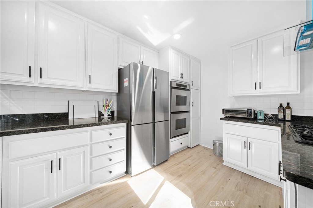 60 Willow Tree Lane Irvine, CA 92612 - Photo 9 of 32 a kitchen with white cabinets and stainless steel appliances