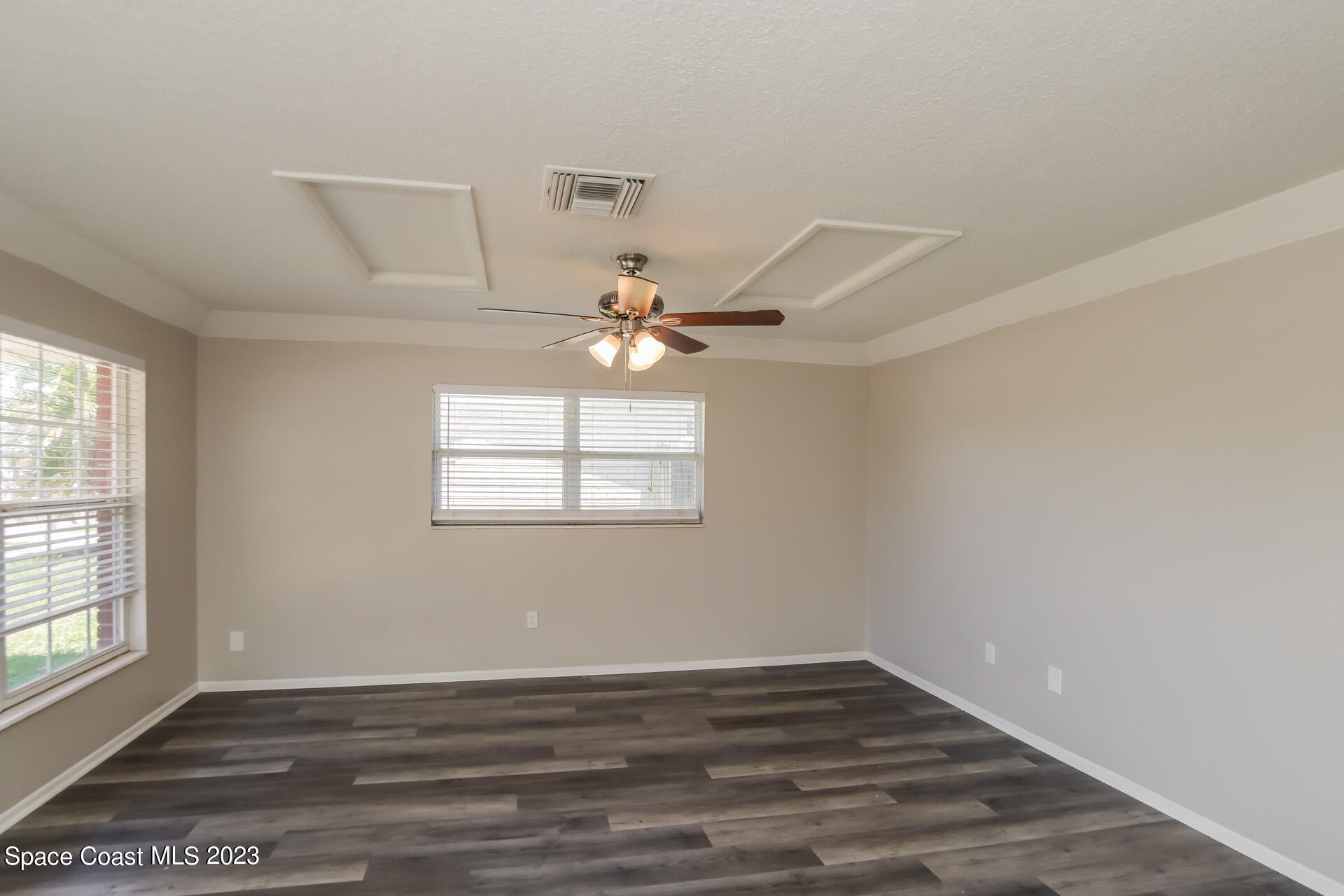 2389 Ricky Road Melbourne, FL 32935 - Photo 4 of 16 an empty room with wooden floor fan and windows