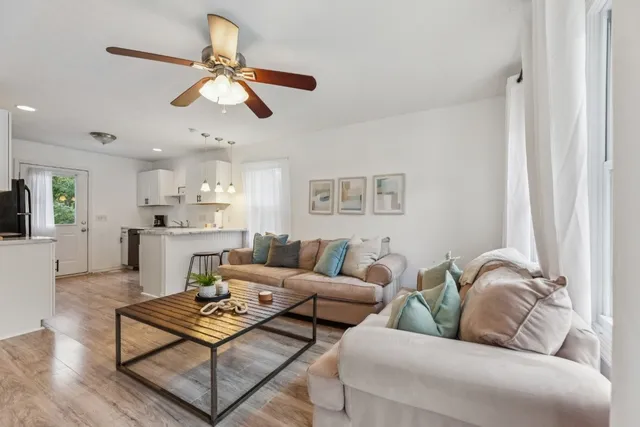 a living room with furniture kitchen view and a chandelier