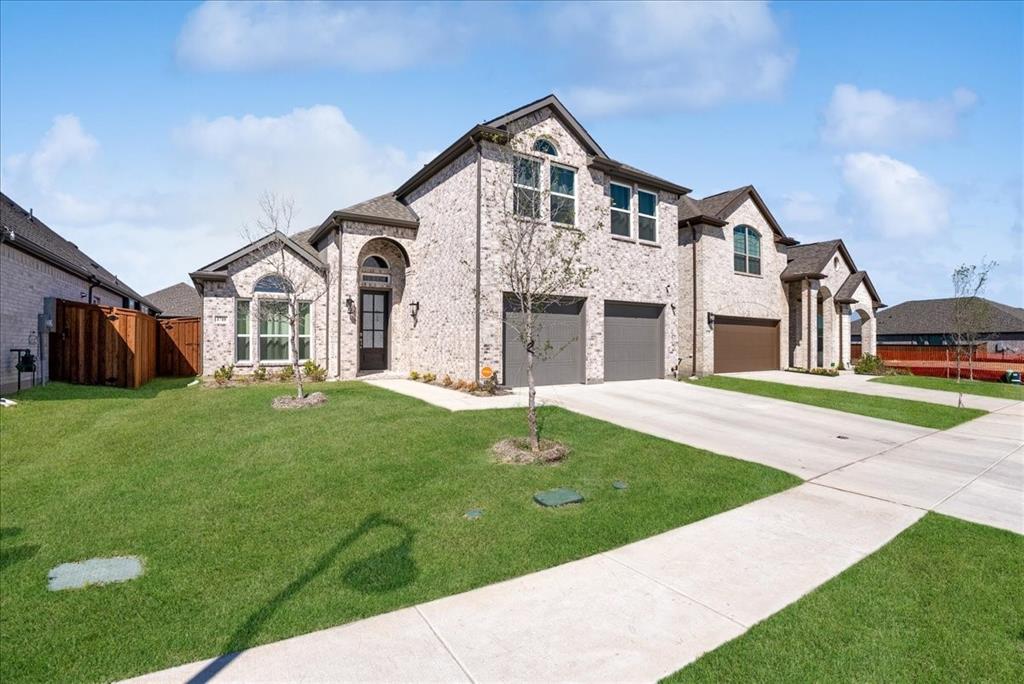 1710 Highwood Road Forney, TX 75126 - Photo 21 of 25 Brick facade residence featuring a two-car garage, arched entry, and a manicured lawn