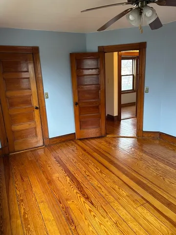 an empty room with wooden floor closet and windows