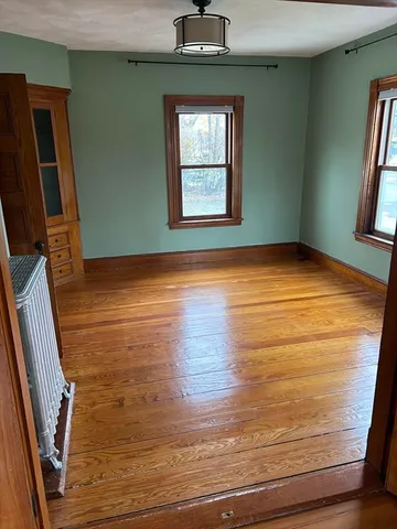 a view of empty room with window and wooden floor