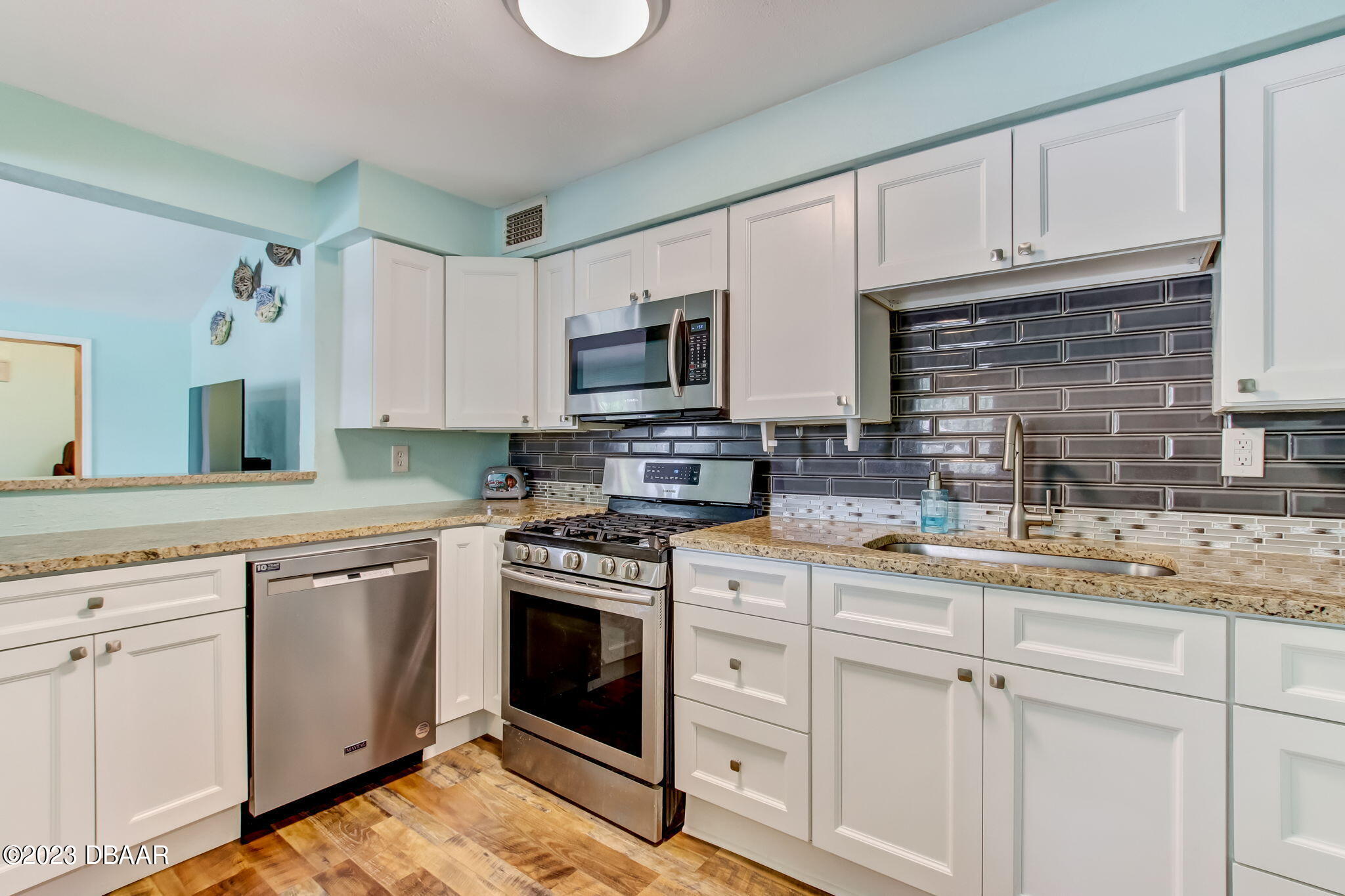 827 South Beach Street Daytona Beach, FL 32114 - Photo 15 of 40 a kitchen with granite countertop white cabinets sink and stainless steel appliances