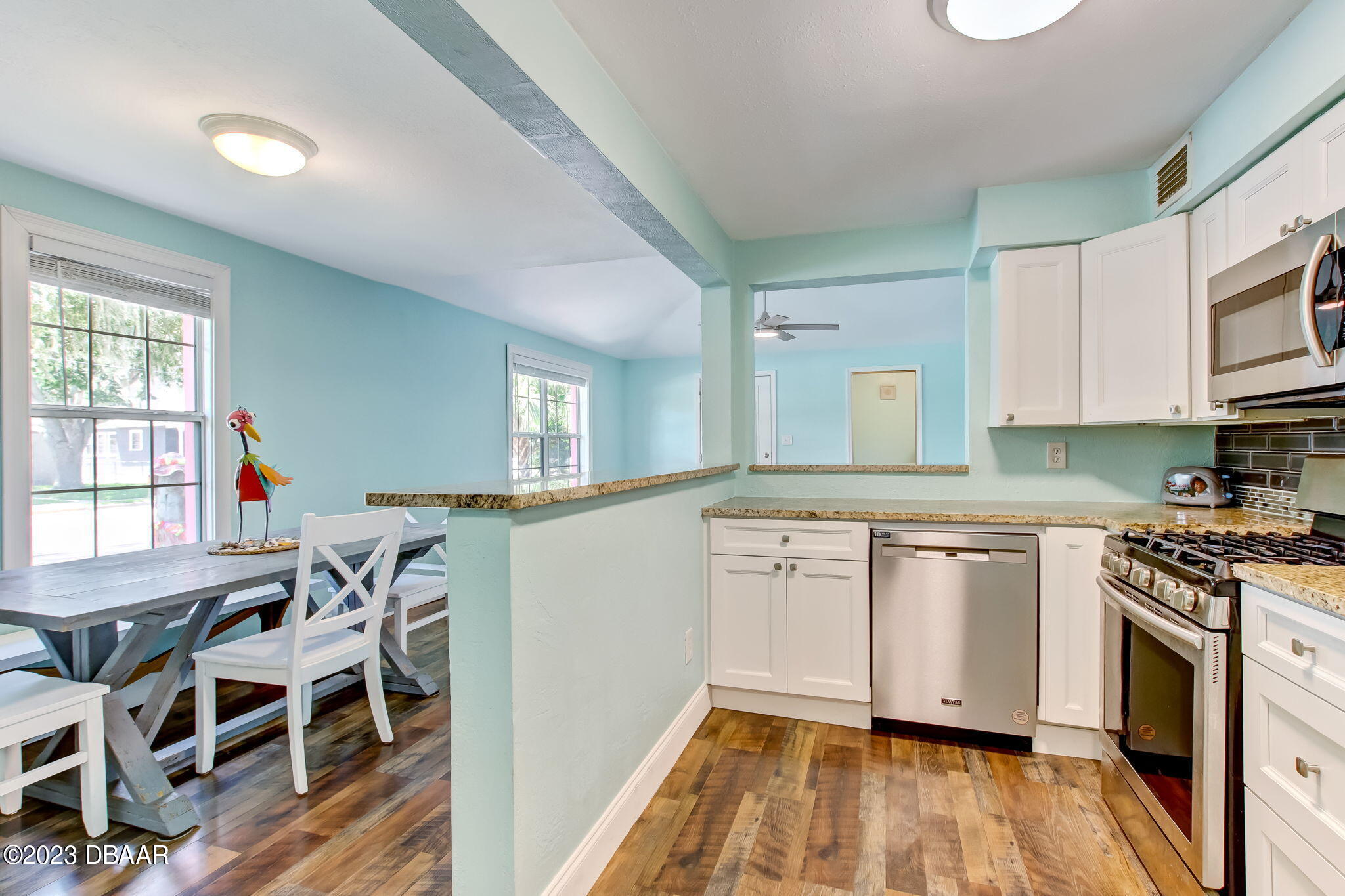 827 South Beach Street Daytona Beach, FL 32114 - Photo 17 of 40 a kitchen with stainless steel appliances granite countertop a stove top oven a sink dishwasher and white cabinets with wooden floor