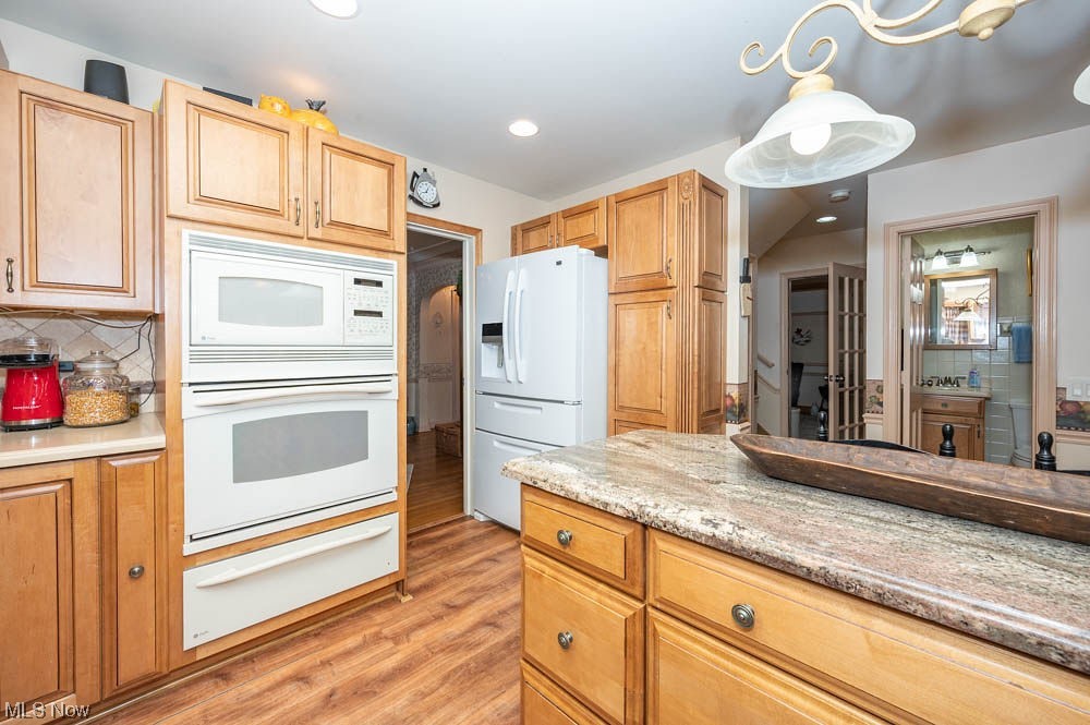 807 North Road Southeast Warren, OH 44484 - Photo 10 of 24 Kitchen with pendant lighting, light stone countertops, white appliances, backsplash, and light wood-type flooring