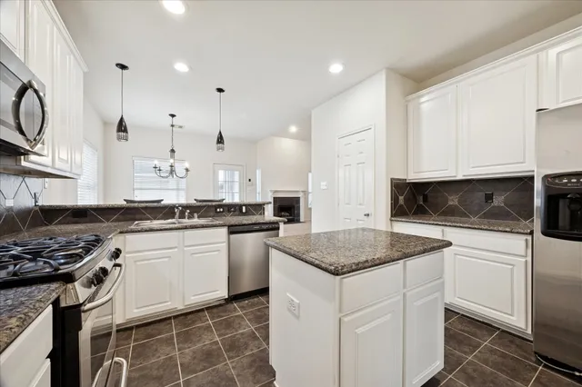 a kitchen with stainless steel appliances granite countertop a stove a sink and a microwave