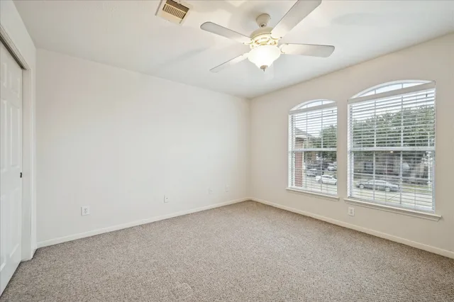 an empty room with windows and fan