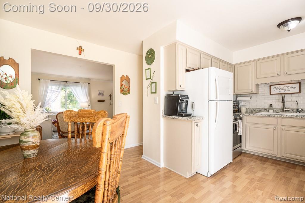 67976 Van Dyke Road, Unit 15 Washington, MI 48095 - Photo 15 of 35 Kitchen featuring wood-finish flooring, light-toned cabinetry, a white subway tile backsplash, and light-toned countertops