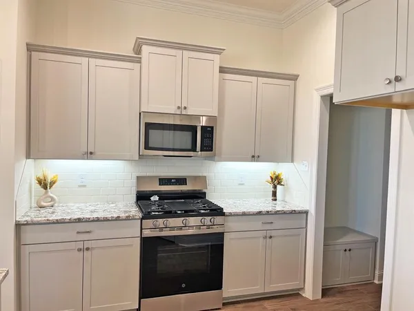 a kitchen with granite countertop white cabinets and stainless steel appliances