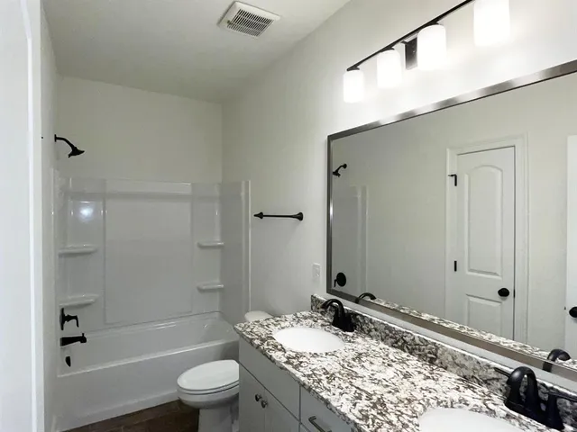 a bathroom with a granite countertop sink toilet and shower