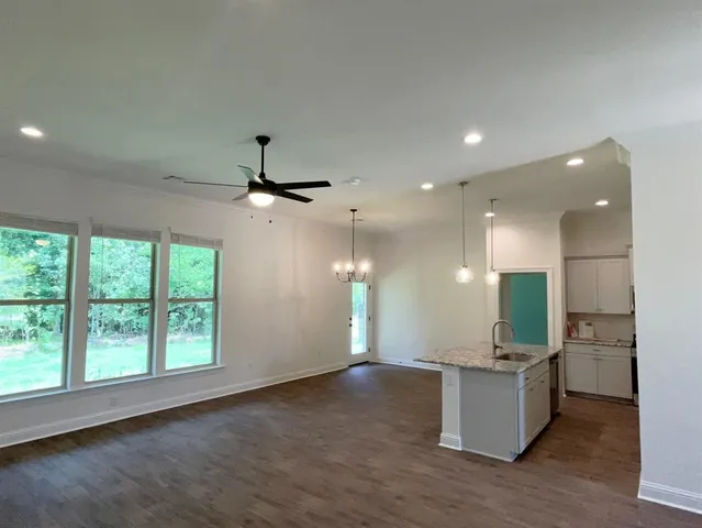 a view of a kitchen with granite countertop a large counter top space appliances and a ceiling fan