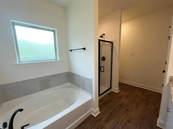 a view of a hallway with wooden floor and a bathroom