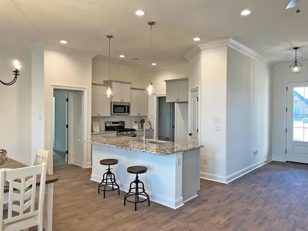 a view of kitchen with kitchen island stainless steel appliances refrigerator stove dining table and chairs