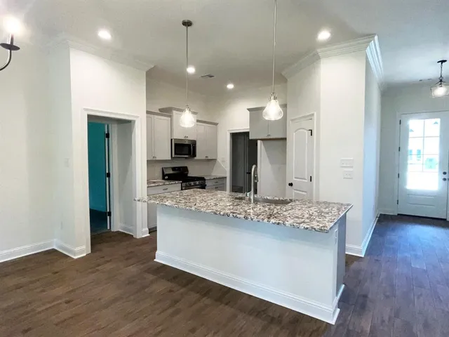 a large kitchen with stainless steel appliances kitchen island a large counter top and a wooden floors