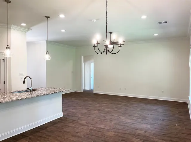 a view of a room with wooden floor and kitchen view