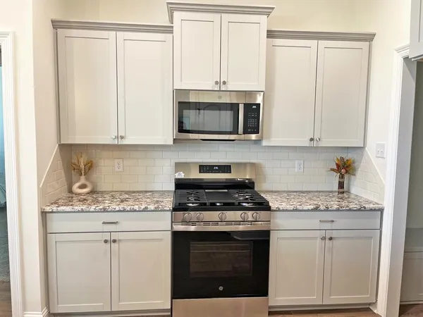 a kitchen with granite countertop white cabinets and stainless steel appliances