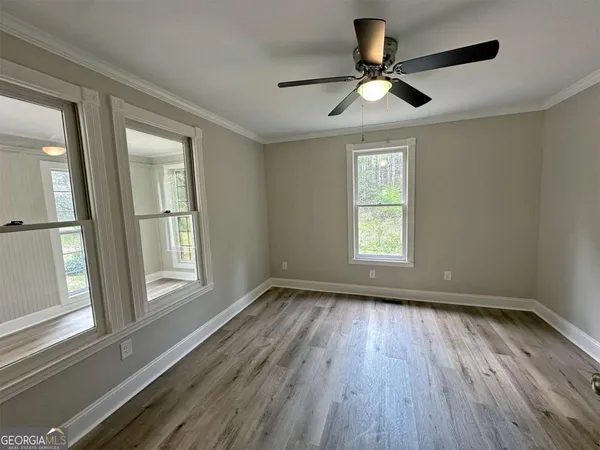 a view of empty room with wooden floor and fan