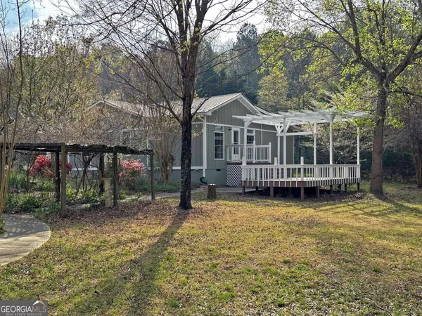 a view of a house with a yard and large trees