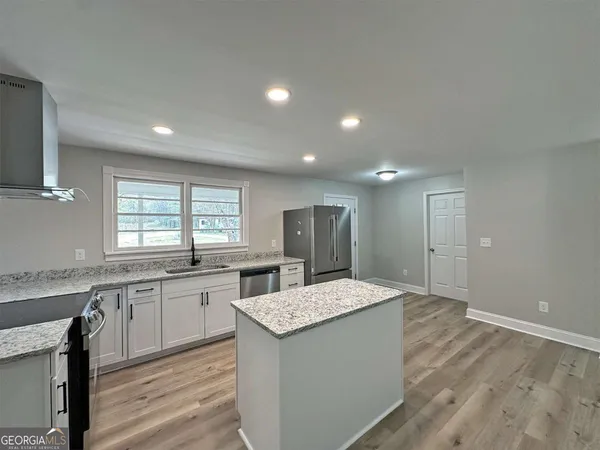 a large kitchen with granite countertop a sink and dishwasher a stove with wooden floor