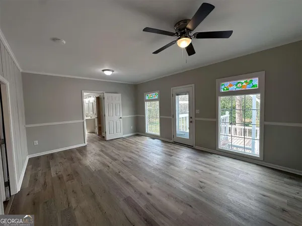 a view of an empty room with wooden floor and a window