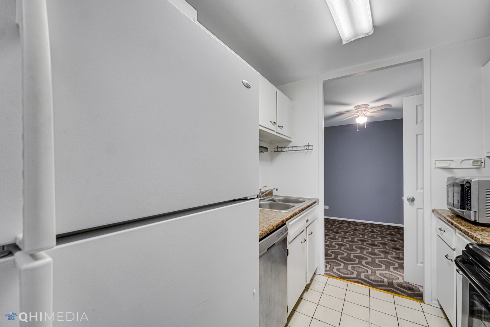 5740 North Sheridan Road, Unit 12C Chicago, IL 60660 - Photo 14 of 19 a kitchen with white cabinets and white appliances