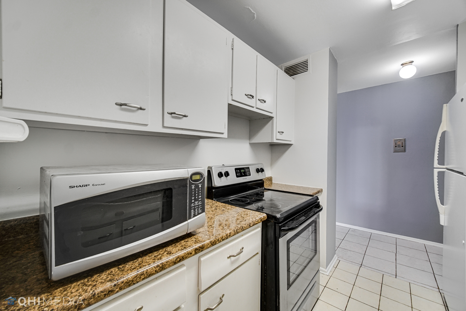 5740 North Sheridan Road, Unit 12C Chicago, IL 60660 - Photo 15 of 19 a kitchen with granite countertop white cabinets and stainless steel appliances