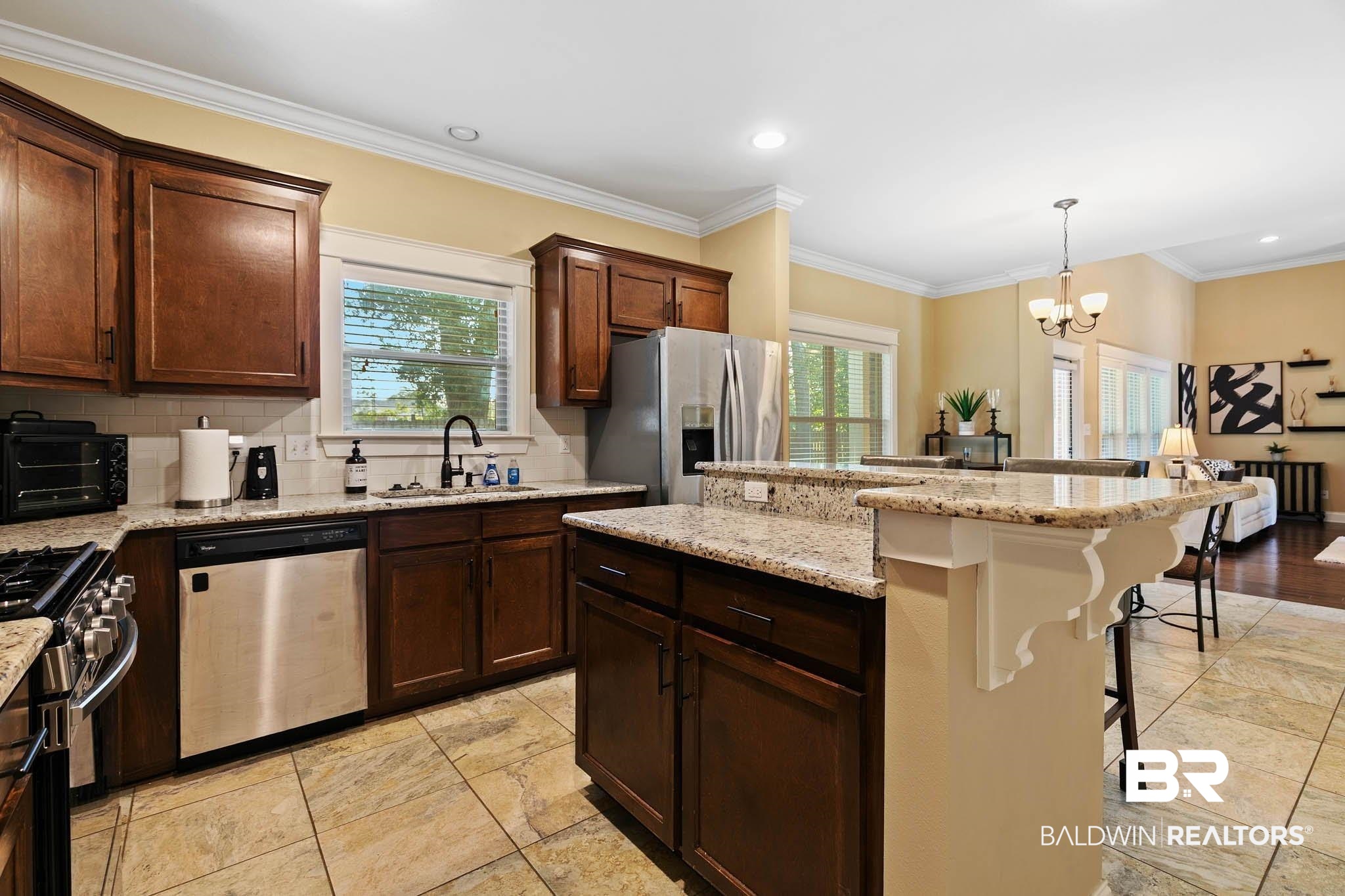 19740 Bunker Loop Fairhope, AL 36532 - Photo 12 of 33 Kitchen featuring crown molding, a kitchen breakfast bar, stainless steel appliances, a chandelier, and decorative backsplash