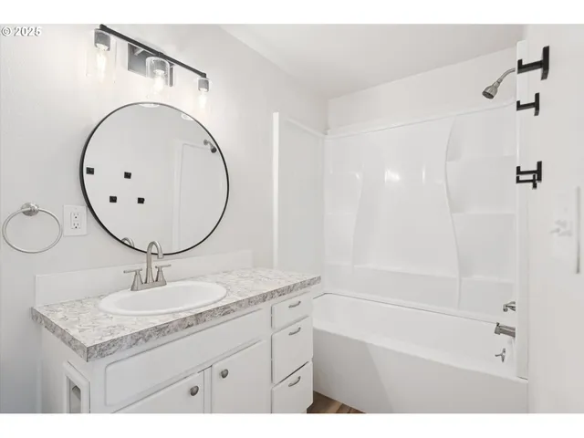 a bathroom with a granite countertop sink a mirror and a shower