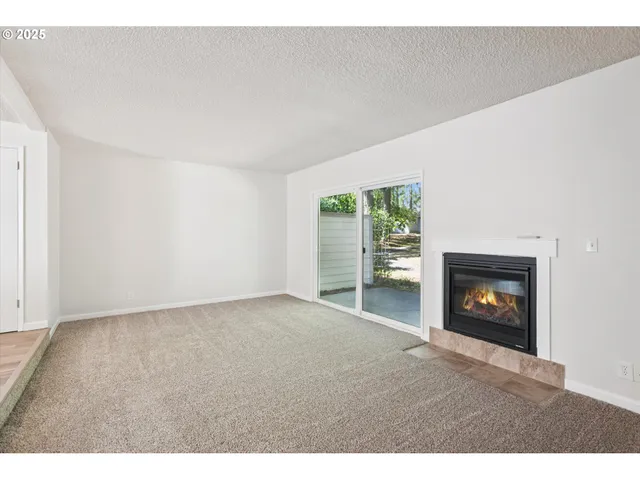 a view of an empty room with a fireplace and a window