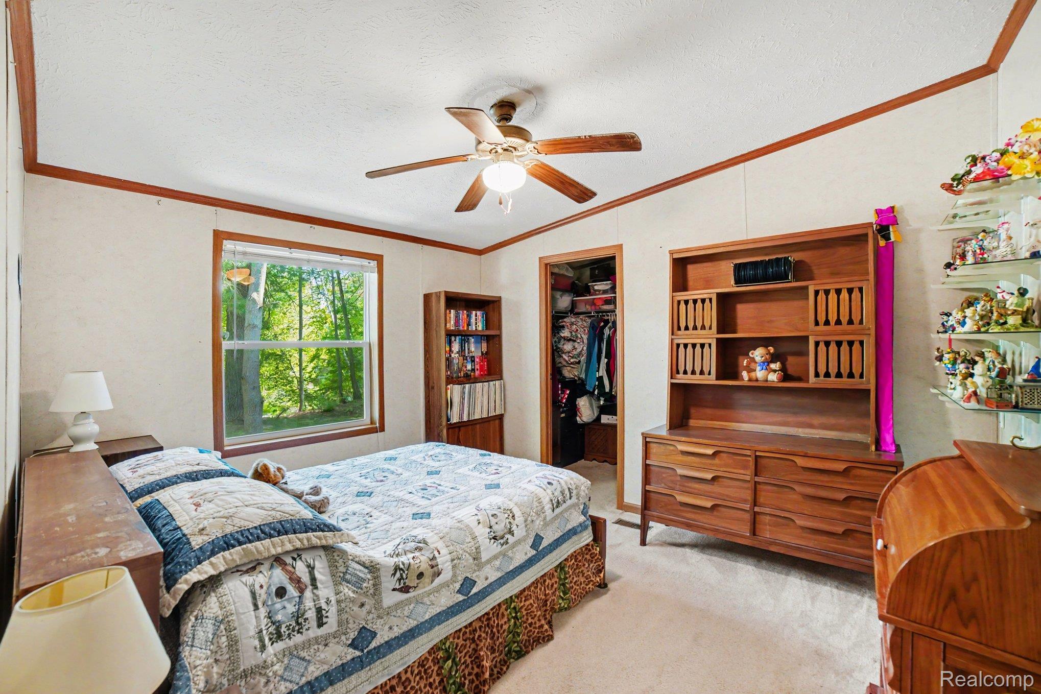 4772 South Bard Road Beaverton, MI 48612 - Photo 21 of 46 Carpeted room featuring a ceiling fan, a window with natural light, a wood-finish built-in bookcase, and a visible closet entrance