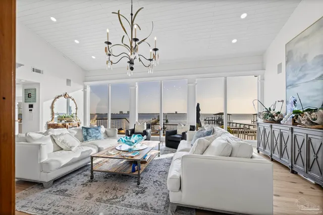 a living room with furniture a rug kitchen view and a large window