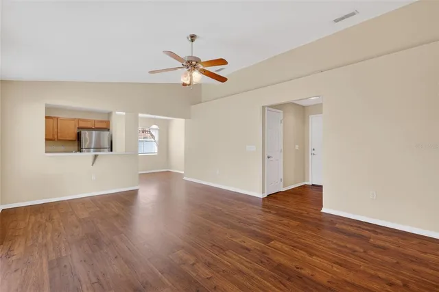 a view of empty room with wooden floor and ceiling fan