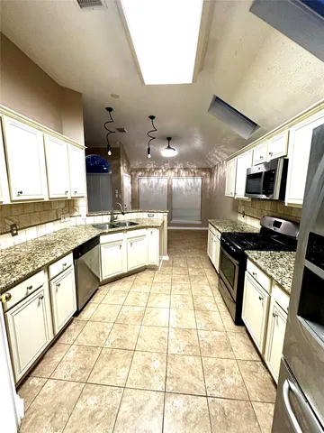 a large kitchen with stainless steel appliances kitchen island granite countertop a large counter top space a sink a stove a washer and dryer