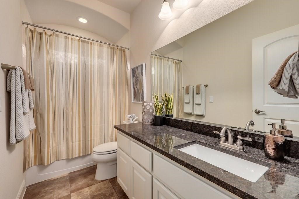 10825 Ballard Path Austin, TX 78717 - Photo 33 of 39 a bathroom with a granite countertop sink a toilet a mirror and shower curtain