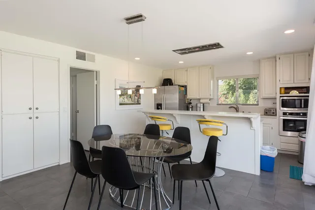 a kitchen with stainless steel appliances granite countertop a sink a stove a refrigerator a microwave a island and chairs