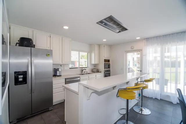 a kitchen with stainless steel appliances kitchen island granite countertop a table chairs in it and wooden floors