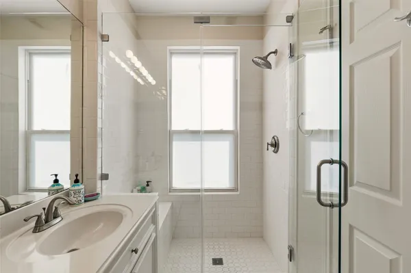 a bathroom with a glass door shower a mirror and a sink